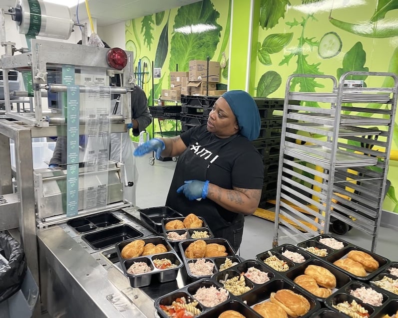 A worker and volunteer with Open Hand package food at the nonprofit's facility in Grove Park. (Alyssa Johnson/Capital B)