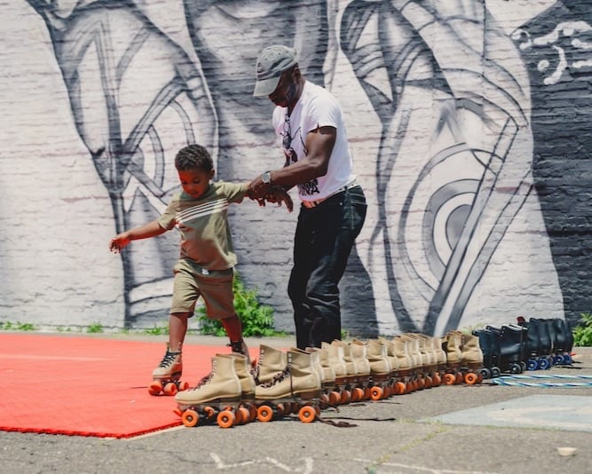 Capone Harris, 3, gets help maintaining his balance at the pop-up skating rink, which was sponsored by the Gary Arts Council. (Javonte Anderson/Capital B)